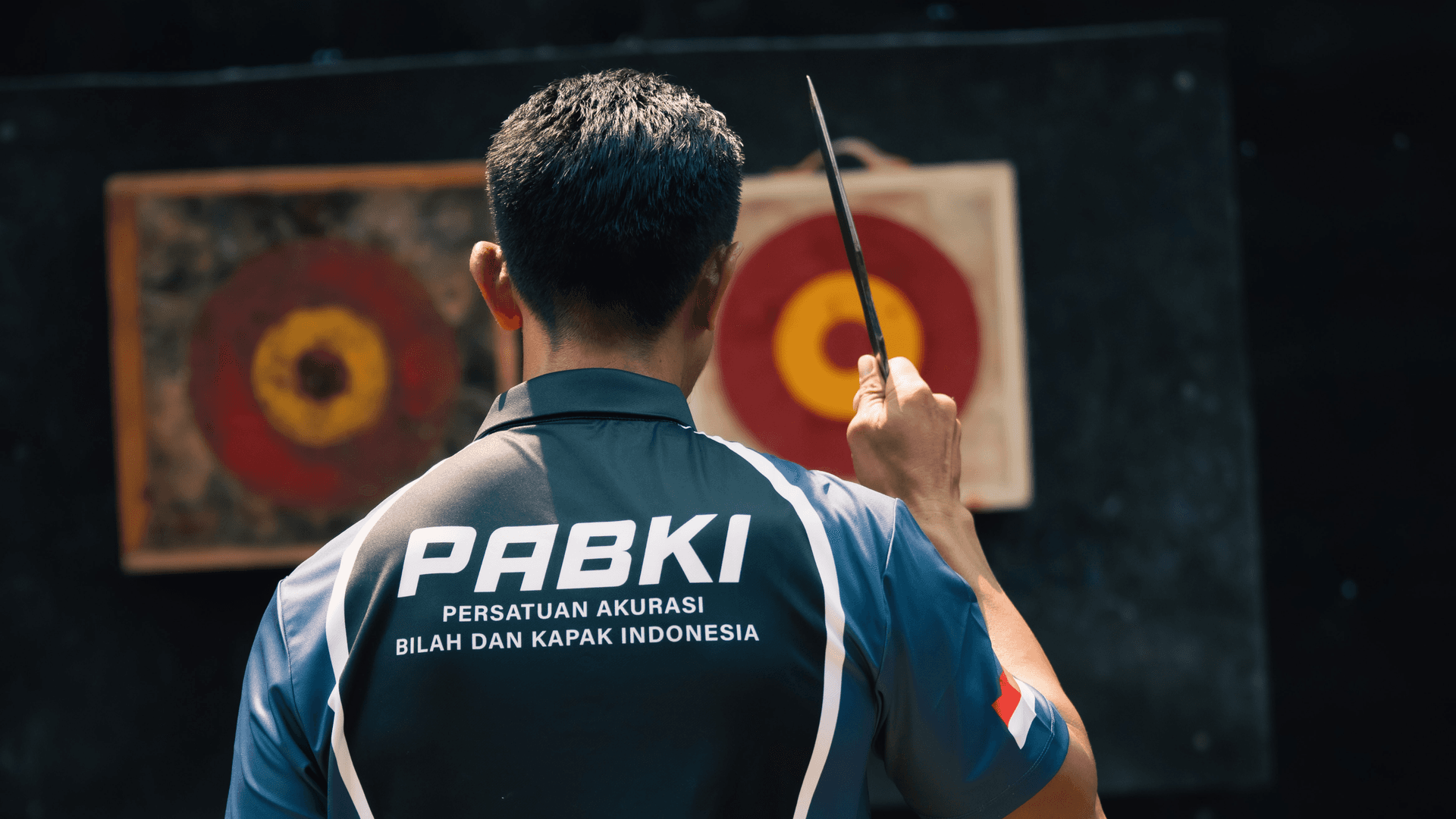 Orang melempar kapak ke target di halaman belakang